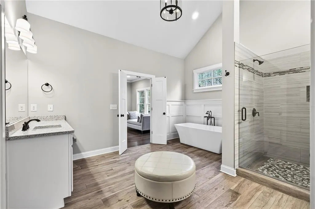 Ensuite bathroom with a stall shower, light wood-style flooring, a freestanding tub, vanity, and high vaulted ceiling