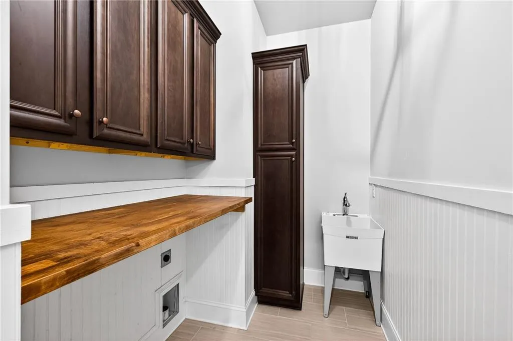 Laundry room off Kitchen with cabinet space, electric dryer hookup, and a wainscoted wall