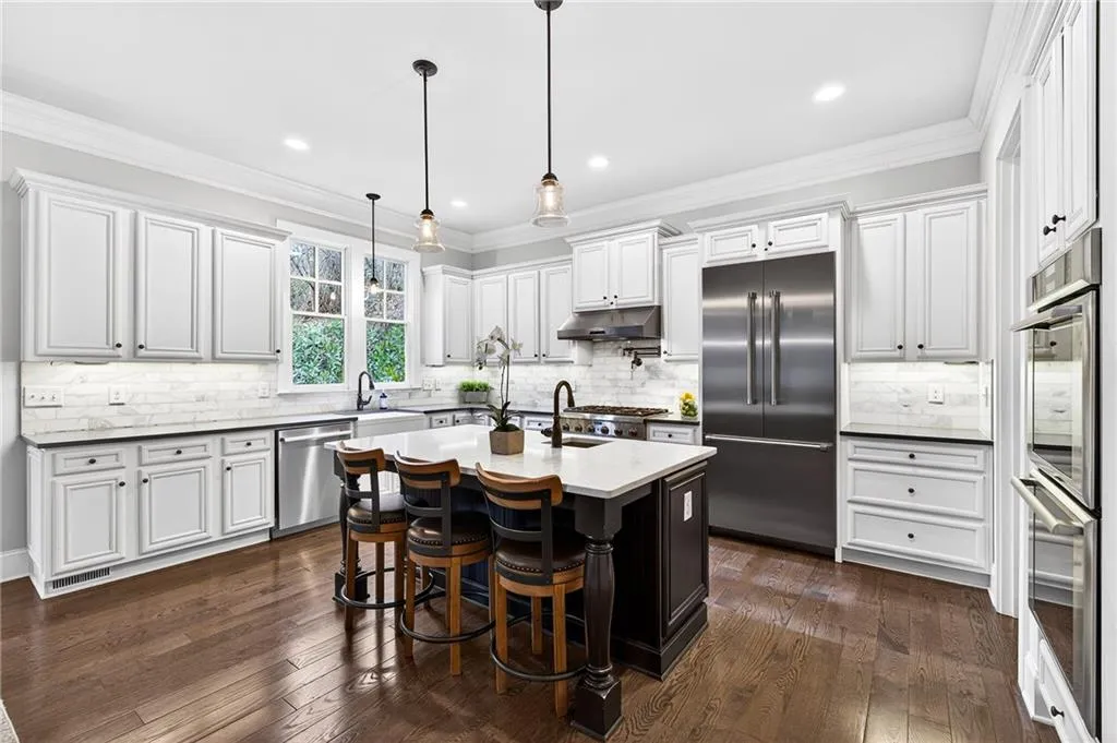 Open and bright kitchen with stainless appliances including double ovens and gas range
