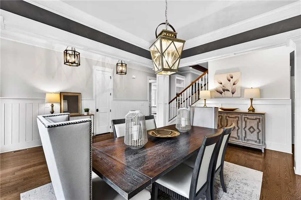 Dining space featuring wainscoting, ornamental molding, dark wood flooring, and a trey ceiling