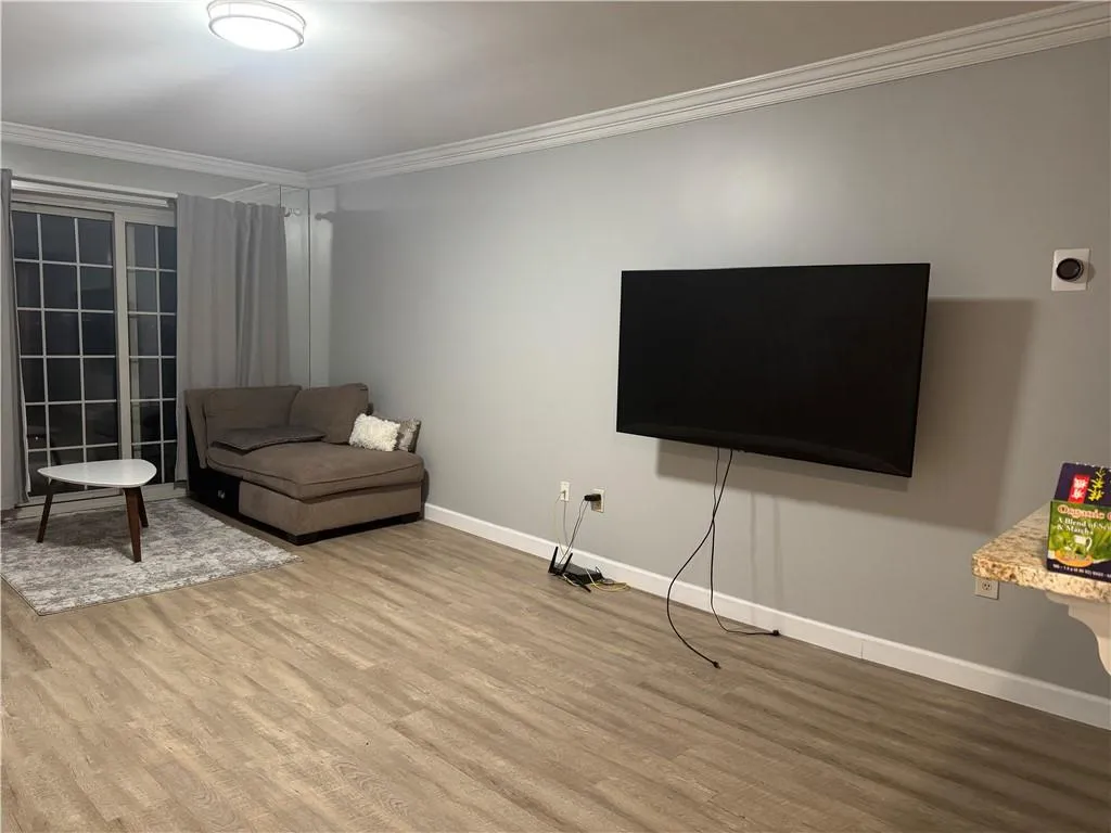 Living area with crown molding and wood finished floors