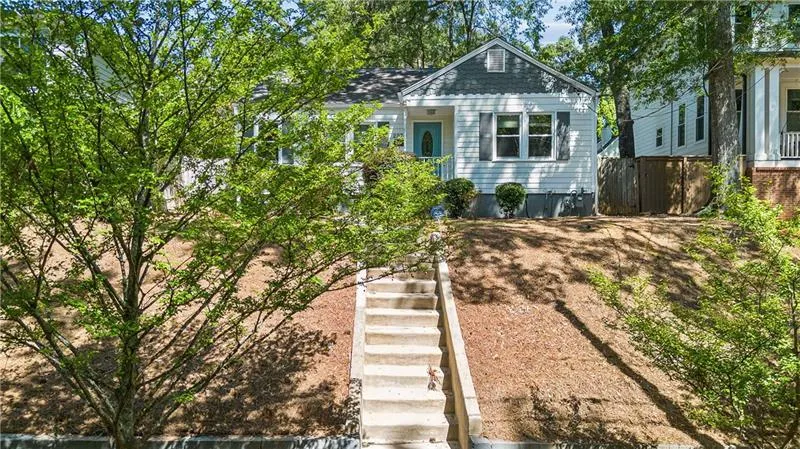 White exterior siding with dark shutters, front gable roof, covered entry, and a multi-level concrete staircase leading to the entrance