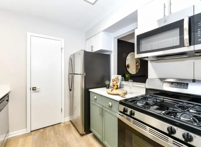 Kitchen featuring stainless steel appliances, green cabinetry, and light wood-style flooring
