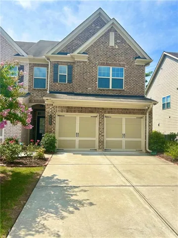 Brick exterior with a gabled roofline, two-car garage, concrete driveway, and front landscaping