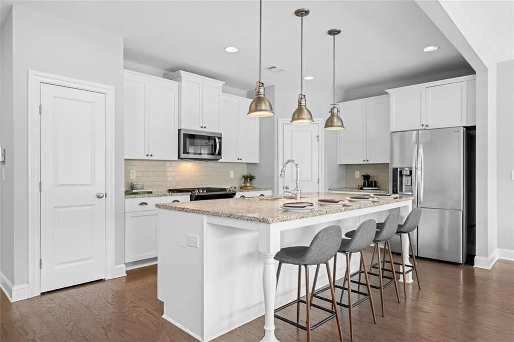 Kitchen with stainless steel appliances, dark wood-style floors, backsplash, hanging light fixtures, and recessed lighting