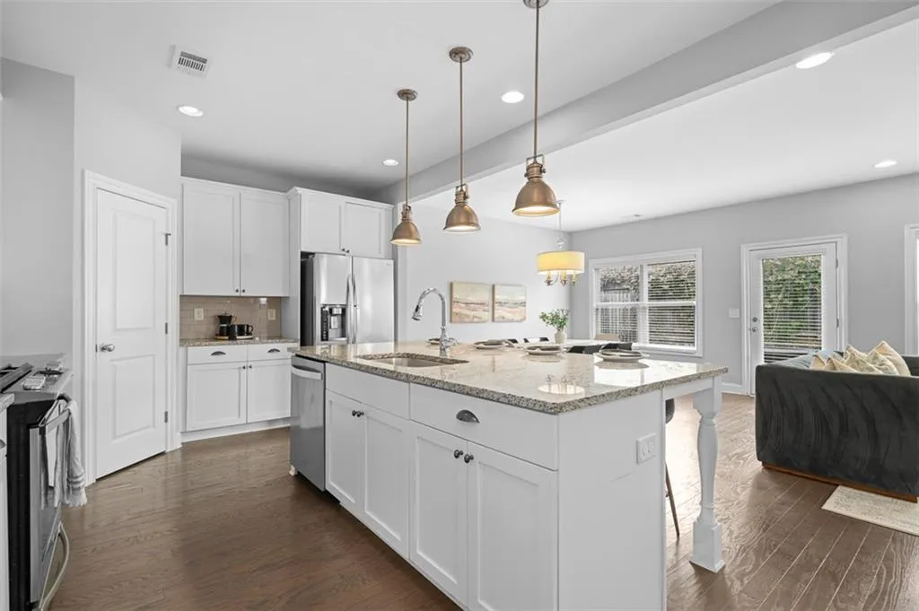 Kitchen with dark wood finished floors, stainless steel appliances, light stone counters, backsplash, and recessed lighting
