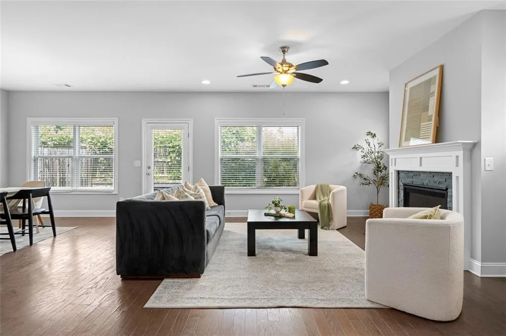 Living area with plenty of natural light, dark wood finished floors, a ceiling fan, a glass covered fireplace, and recessed lighting
