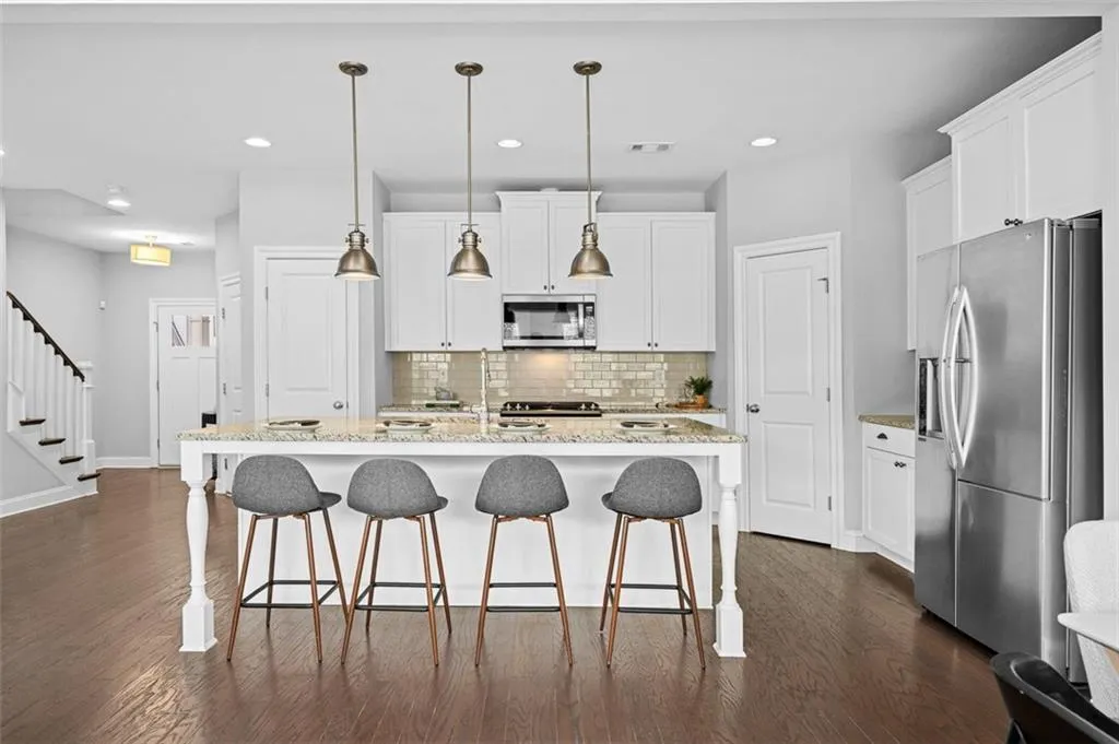 Kitchen featuring stainless steel appliances, decorative backsplash, white cabinetry, and recessed lighting