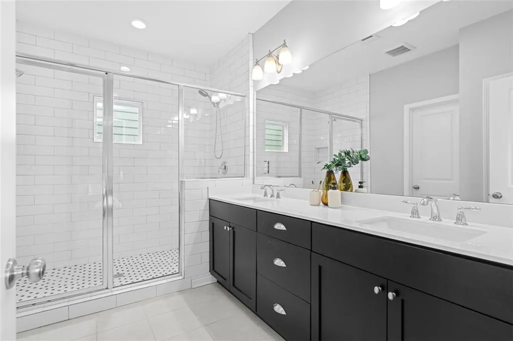 Full bath with double vanity, a shower stall, and tile patterned flooring