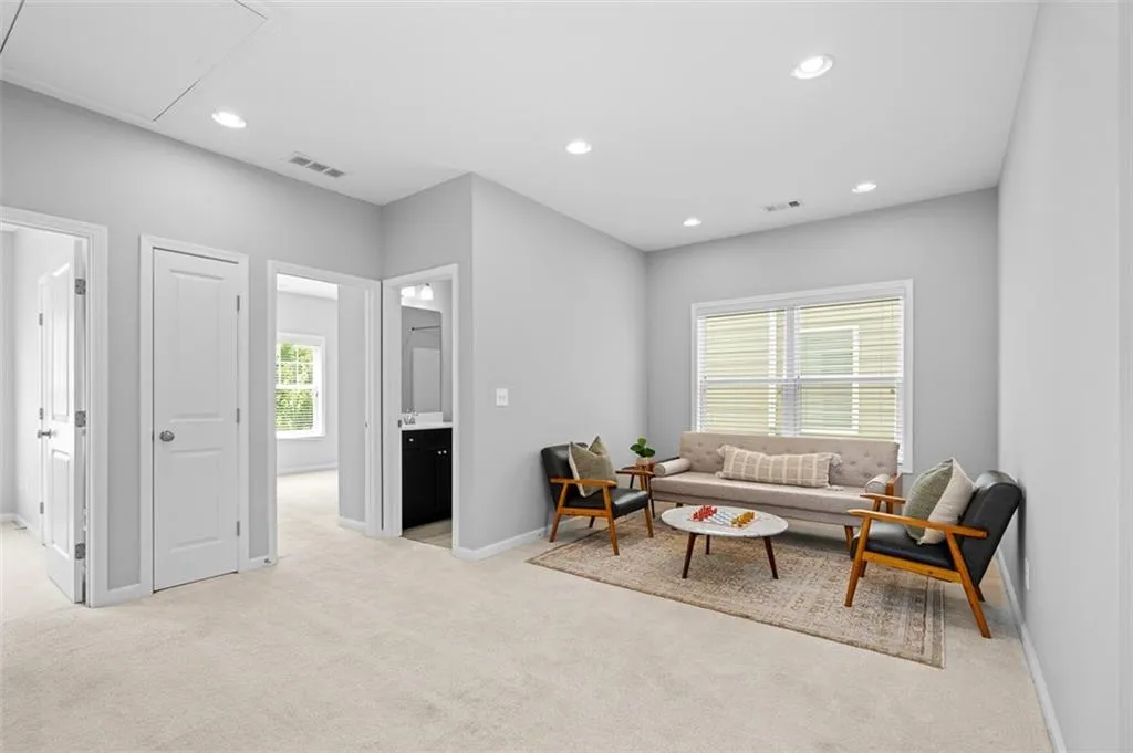 Living room with light carpet, recessed lighting, and attic access