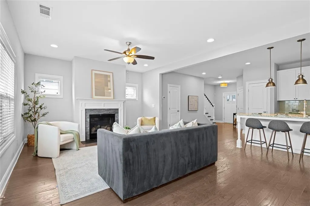 Living area with dark wood-type flooring, a stone fireplace, stairs, healthy amount of natural light, and recessed lighting