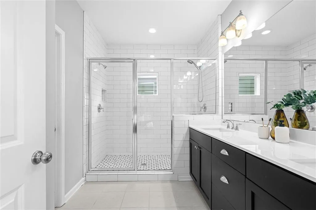 Full bathroom with a shower stall, double vanity, tile patterned flooring, and recessed lighting