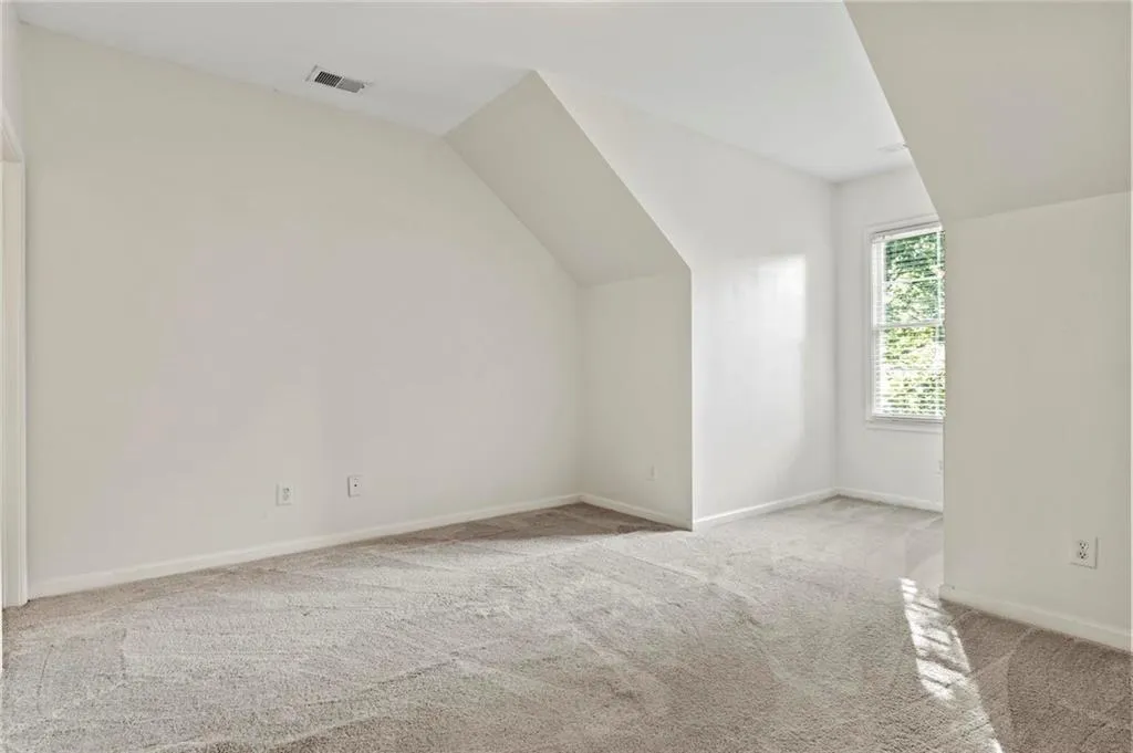 Bedroom 3 room with light colored carpet and lofted ceiling