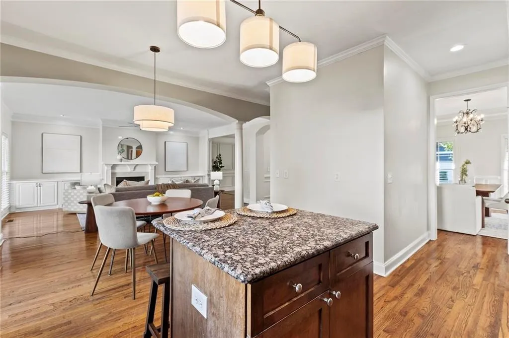 View from Kitchen to Living Room with decorative column, arched walkways, new light fixtures, decorative molding and hardwood floors.