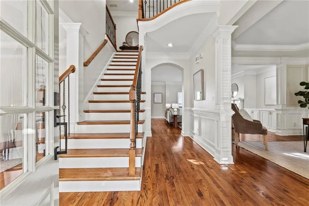 Entryway with arched walkways, decorative molding, stairway, and hardwood floors