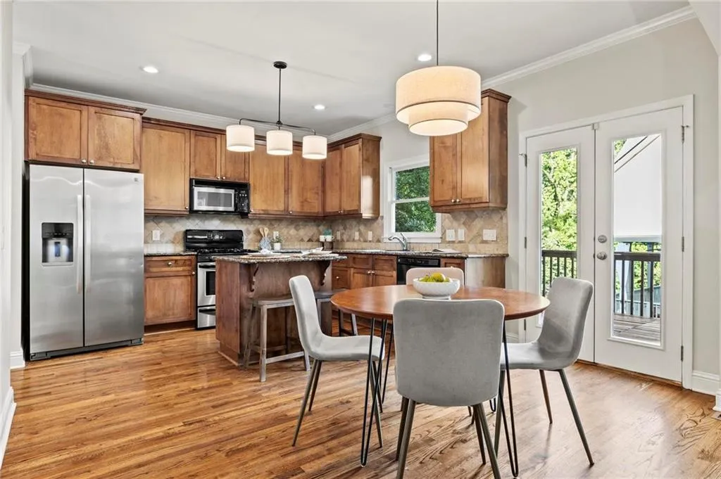 Kitchen with stainless steel appliances, warm wood tone cabinets, crown molding, hardwood floors, granite countertops and backsplash