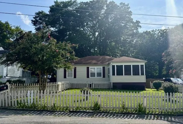 Single-story residence featuring light-colored siding, a gabled roof, and a screened porch