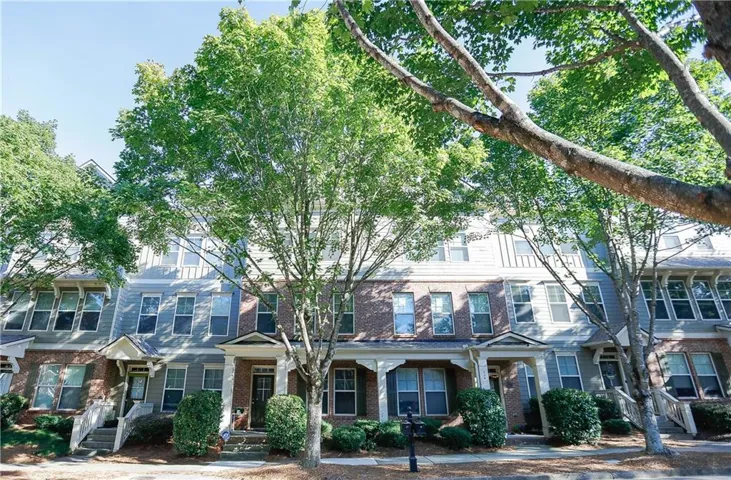 Townhome exterior with brick and siding facade, covered front entry, and mature landscaping
