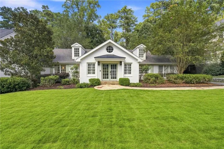 White painted brick exterior with double dormer windows, circular accent window, double entry doors, and a stone entryway