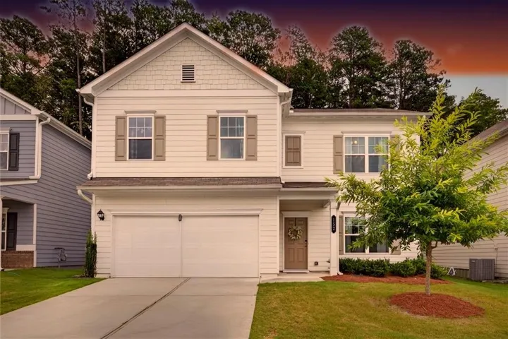 Two-story residence with a two-car garage, concrete driveway, and front door with a decorative wreath
