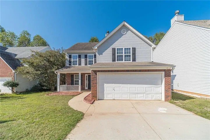 View of front of property featuring a front yard, a garage, and a porch