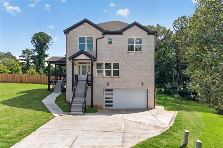 Contemporary style residence featuring light-colored brick exterior, a covered entryway with stairs, and a modern garage door