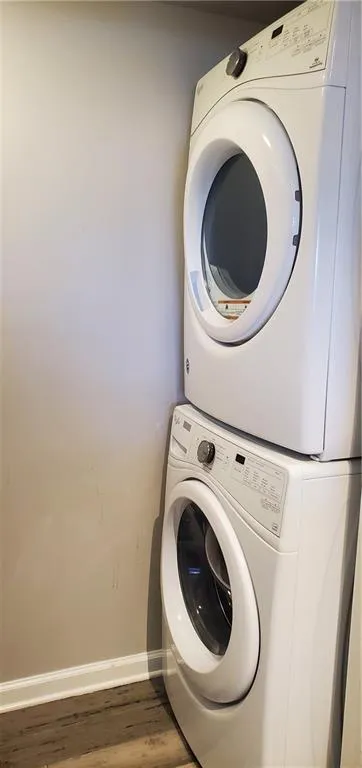 Laundry area featuring hardwood / wood-style flooring and stacked washer and clothes dryer