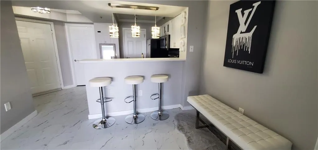 Kitchen with tile patterned flooring, decorative light fixtures, white cabinetry, and kitchen peninsula