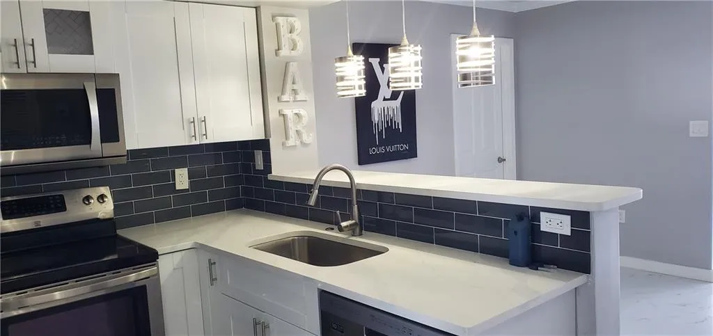 Kitchen featuring sink, tasteful backsplash, white cabinetry, and stainless steel appliances