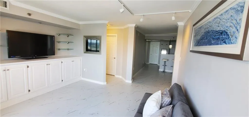Unfurnished living room with crown molding and track lighting