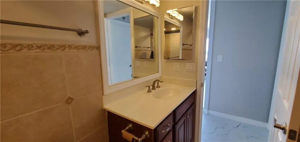 Bathroom with tile patterned flooring, tile walls, and vanity