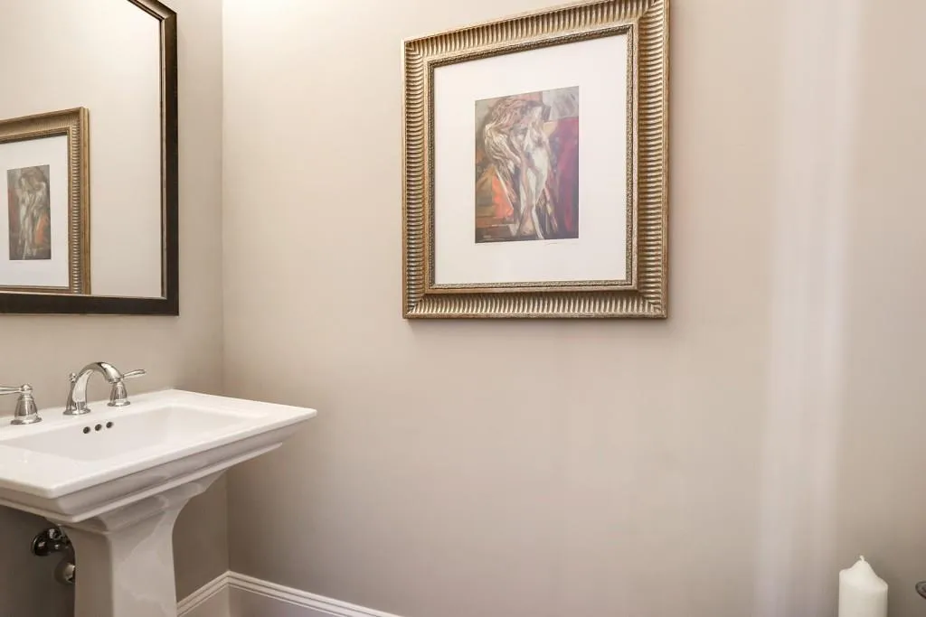 Half bath on main level has custom framed mirror over upgraded Kohler pedestal sink. Upgraded Kohler toilet as well.