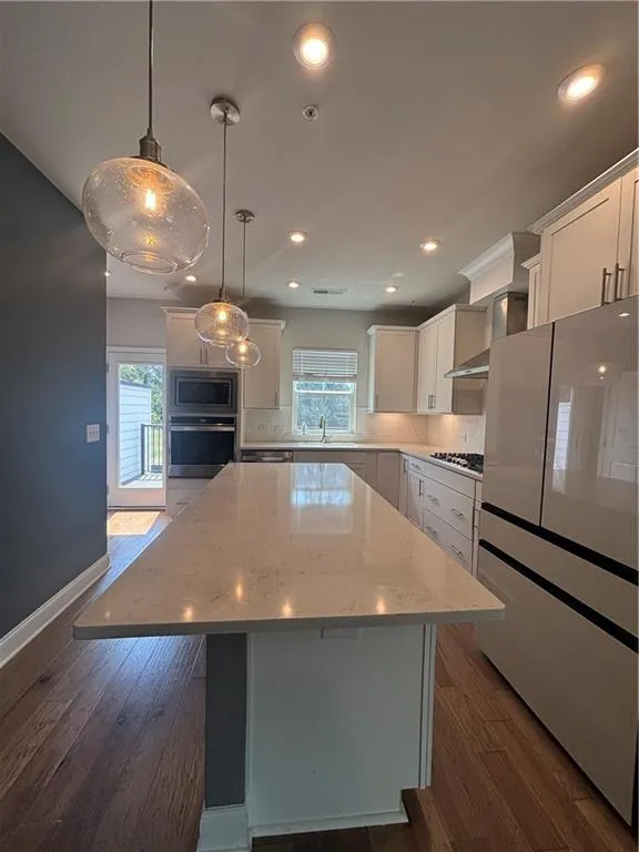Kitchen with a kitchen island, dark wood-style flooring, pendant lighting, white cabinets, and recessed lighting