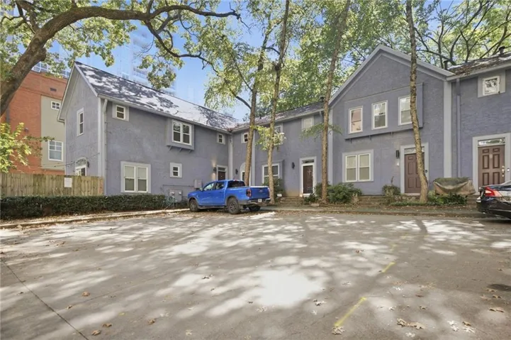 Multi-level exterior with a stucco finish, multiple transom windows, and a dark shingle roof