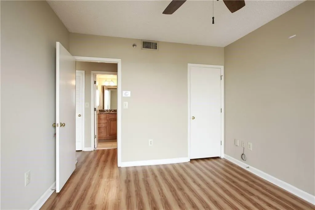 The spacious bedroom offers a panoramic view of Atlantic Station, with a ceiling fan and walk in closet.