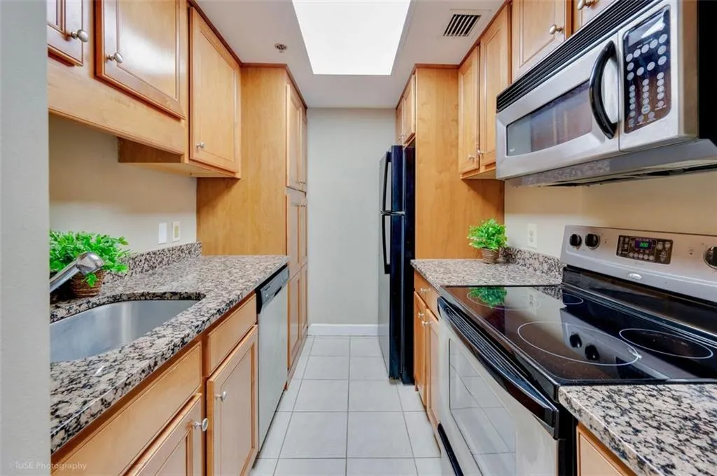 Your quaint galley style kitchen offers an abundance of storage cabinets with stainless steel appliances and granite countertops.