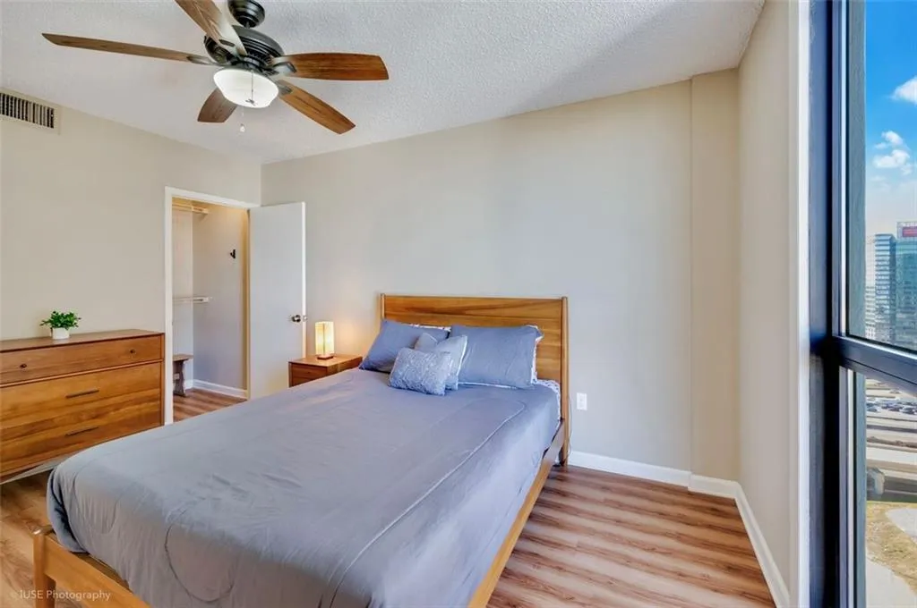 The spacious bedroom offers a panoramic view of Atlantic Station, with a ceiling fan and walk in closet.