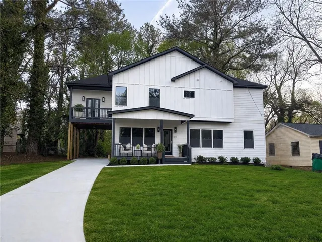 Modern farmhouse style home featuring a front yard, covered porch, driveway, and board and batten siding