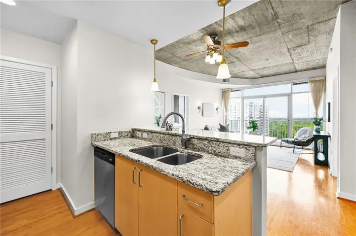 Kitchen island featuring a double basin sink, granite-finish countertops, and wood-finish cabinetry