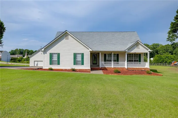 Ranch-style exterior with white siding, green shutters, and a covered front porch featuring white railings