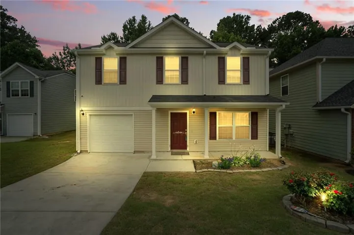 Traditional home with a porch, driveway, an attached garage, and a lawn