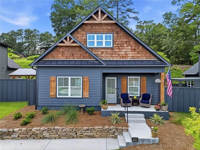 Craftsman-style exterior featuring blue siding, cedar shake gables, and a dark standing seam metal roof