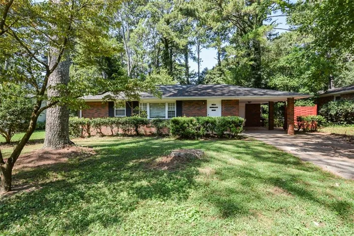 Brick exterior with a covered entryway, mature trees, and established shrubs