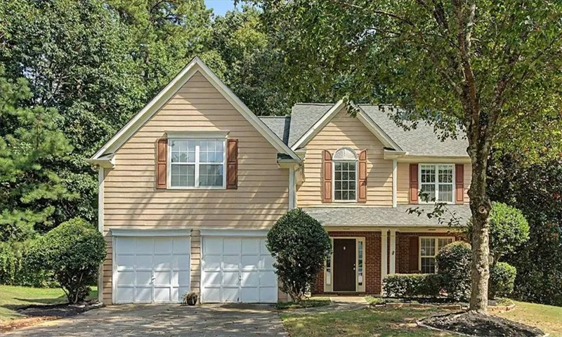Two-story residence featuring light-toned siding and a prominent two-car garage