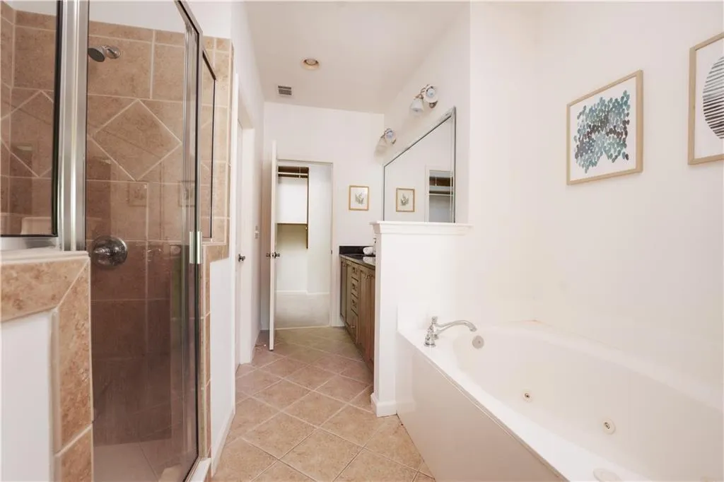 Bathroom with vanity, a jetted tub, a shower stall, and light tile patterned flooring