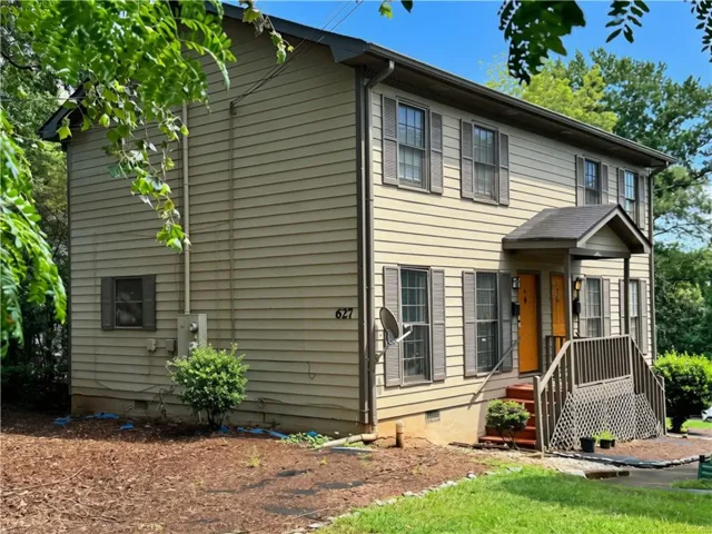 Two-story structure with horizontal siding, multiple windows with shutters, and a covered porch entry