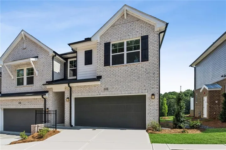 Modern two-story brick residence featuring a prominent front-facing gable with large multi-pane windows, dark-trimmed architectural detailing, and a three-car garage with dark panel doors