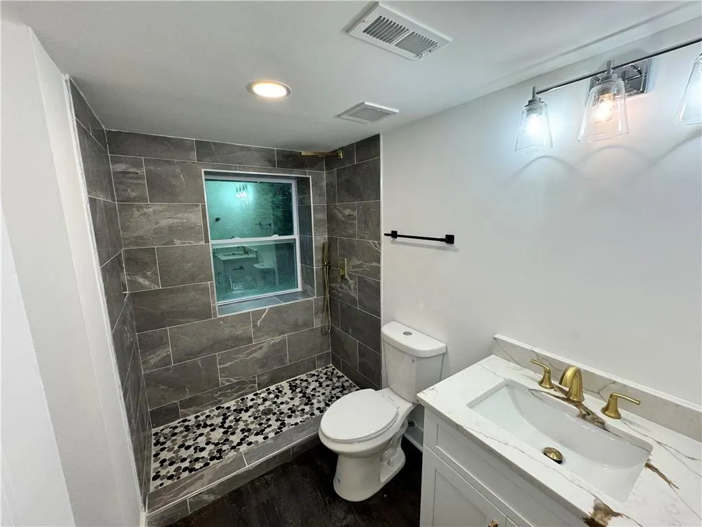 Bathroom with vanity, a tile shower, and toilet