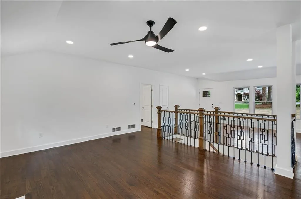 Spare room featuring dark wood-type flooring, vaulted ceiling, and ceiling fan