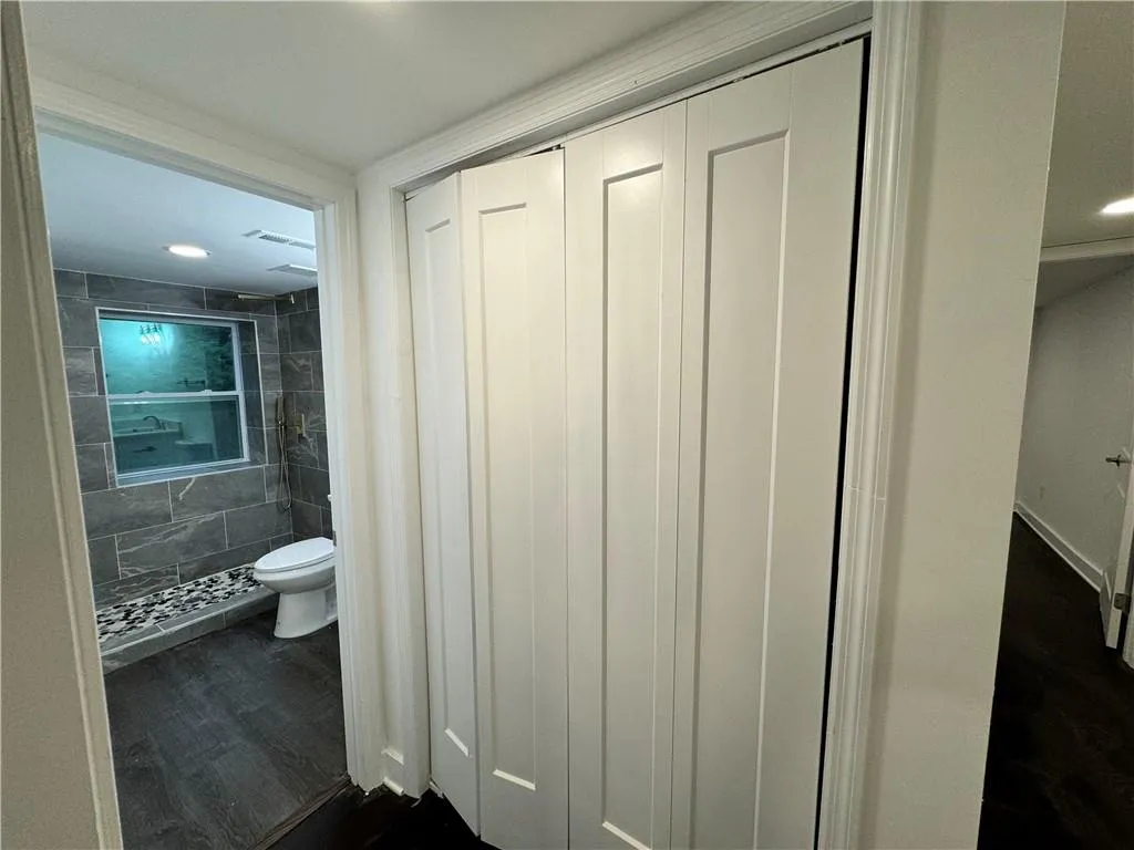 Bathroom with toilet, walk in shower, hardwood / wood-style floors, and tile walls